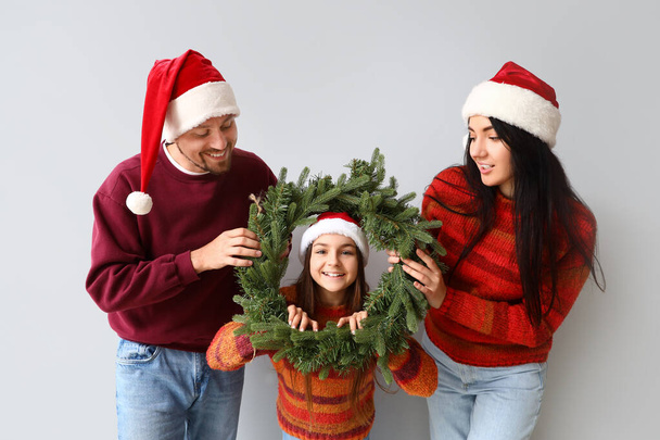 Glückliche Familie mit Weihnachtskranz auf hellem Hintergrund - Foto, Bild
