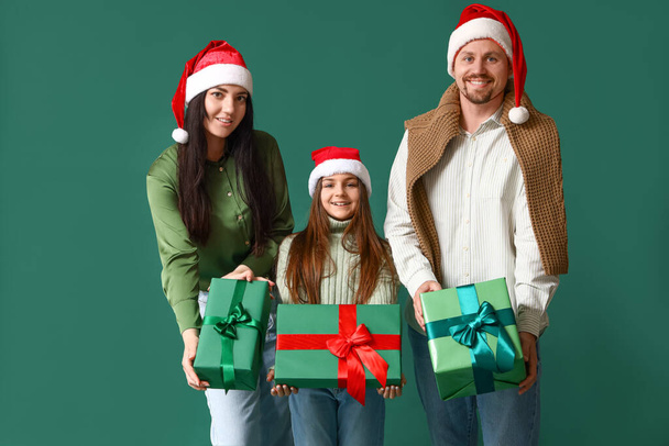 Glückliche Familie mit Weihnachtsgeschenken auf grünem Hintergrund - Foto, Bild