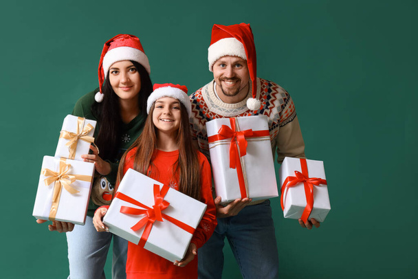 Gelukkig gezin met kerstcadeaus op groene achtergrond - Foto, afbeelding