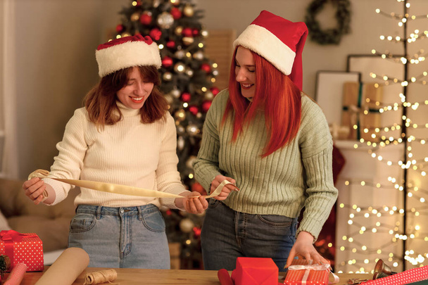 Młode kobiety ze wstążką na prezent świąteczny w domu - Zdjęcie, obraz