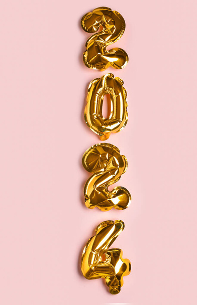 Gouden folie ballonnen nummer 2024 op roze achtergrond. Nieuwjaarsconcept. - Foto, afbeelding