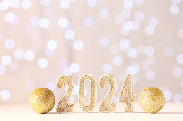 Obrázek 2024 s vánočními míčky na stole proti rozmazaným světlům - Fotografie, Obrázek