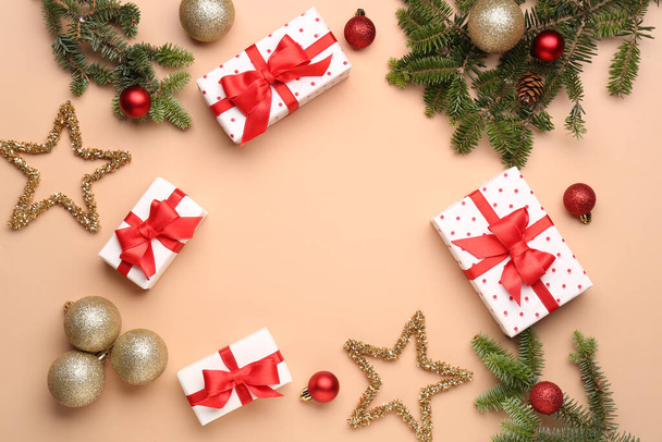 Χριστουγεννιάτικα κλαδιά δέντρων με κουτιά δώρων, μπάλες και διακοσμήσεις σε μπεζ φόντο - Φωτογραφία, εικόνα