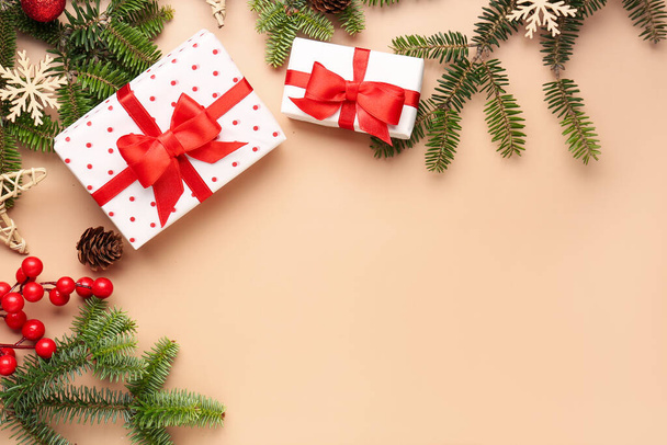 Kerst boom takken met geschenkdozen, rowan en decoraties op beige achtergrond - Foto, afbeelding