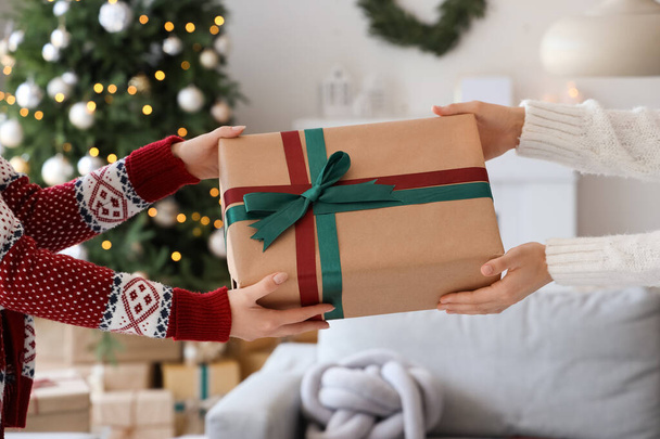 Γυναίκα λαμβάνει δώρο κουτί από το φίλο της στο σπίτι την παραμονή των Χριστουγέννων, closeup - Φωτογραφία, εικόνα