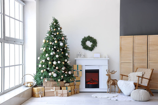 Interieur van de feestelijke woonkamer met geschenkdozen onder de kerstboom - Foto, afbeelding