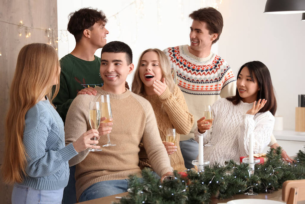 Group of young people with champagne celebrating Christmas in kitchen - Photo, Image