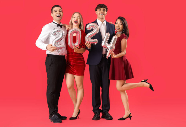 Young people with balloons in shape of figure 2024 on red background - Photo, Image