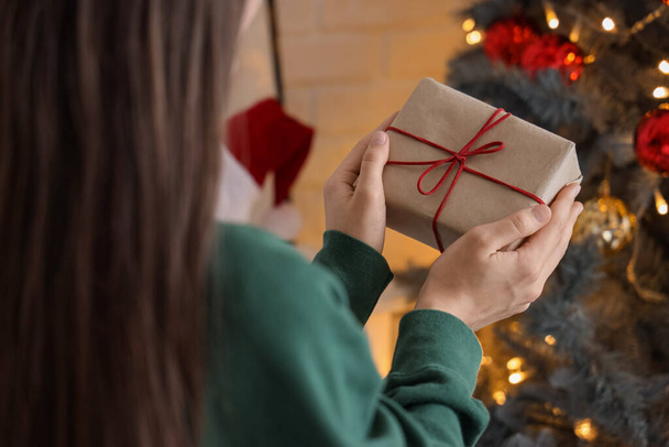 Vrouw met geschenkdoos thuis op kerstavond, close-up - Foto, afbeelding
