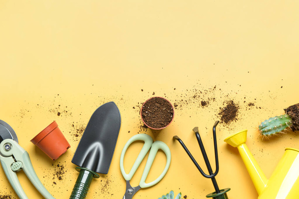 Composición con herramientas de jardinería, suelo y planta sobre fondo amarillo - Foto, Imagen