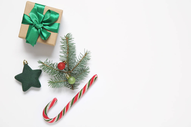 Подарункова коробка, ялинова гілка з різдвяними кульками та цукерками на білому тлі - Фото, зображення