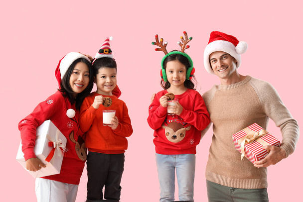 Joyeux famille avec cadeaux de Noël, lait et biscuits sur fond rose - Photo, image