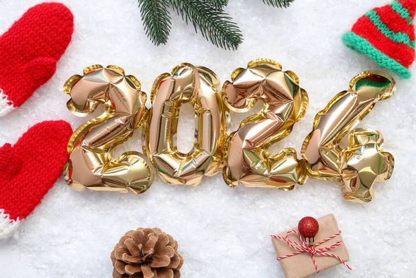 Composizione con figura 2024 realizzata in palloncini di alluminio e decorazioni natalizie su sfondo bianco - Foto, immagini