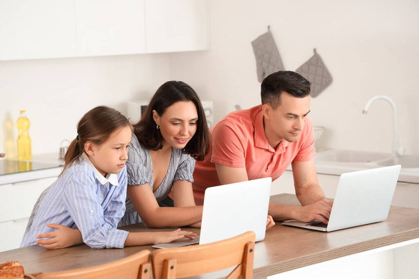 Família com laptops descansando à mesa na cozinha - Foto, Imagem