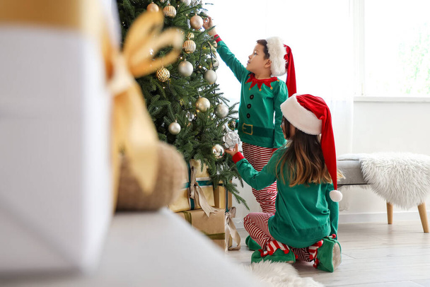 自宅でクリスマスツリーを飾る愛らしい小さな子供 - 写真・画像