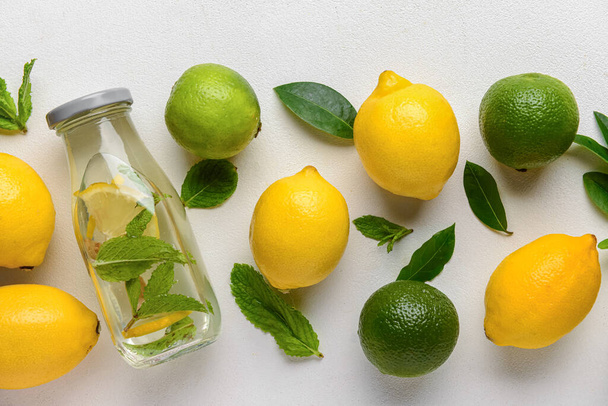 Bottiglia di gustosa limonata con menta e lime su fondo bianco - Foto, immagini