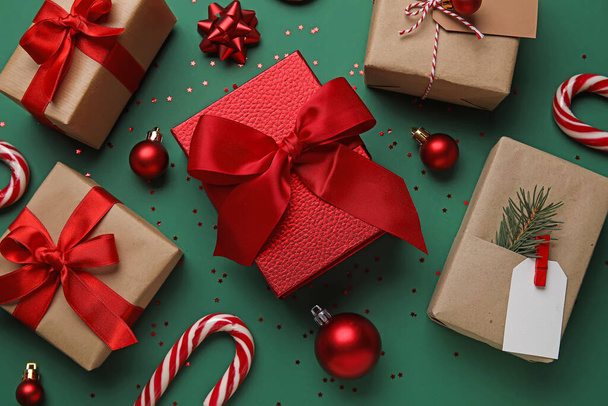 Різдвяні кульки з подарунковими коробками та цукерками на зеленому фоні - Фото, зображення