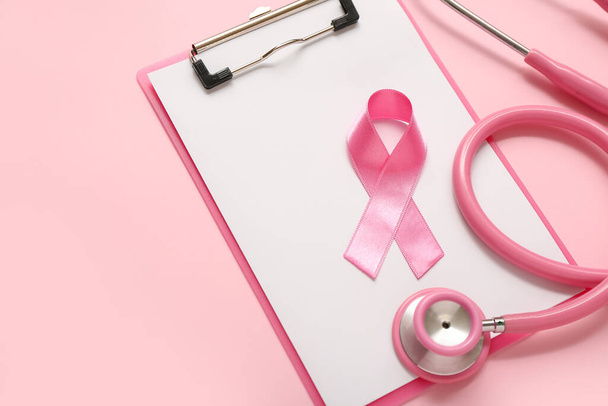 Pink ribbon with stethoscope and clipboard on color background. Breast cancer awareness concept - Photo, Image