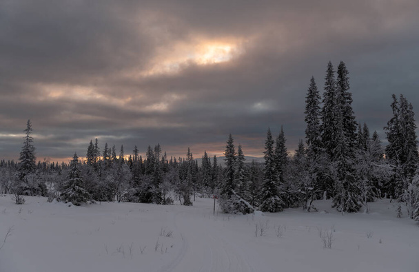 Skandináviában egy téli reggelen napkelte ragyog a felhők között. - Fotó, kép