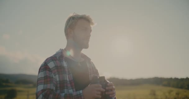 Молодий турист-чоловік дивиться через бінокль на небо в сонячний день - Кадри, відео