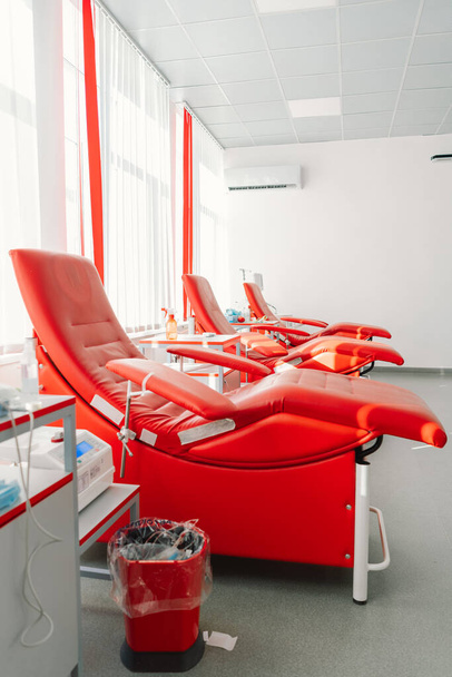 寄付センターに座るための赤いアームチェア. ドナーから血液を採取するための輸血ステーション - 写真・画像