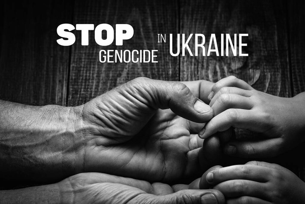 mannelijke handen houden kinderen op een donkere achtergrond met woorden stoppen genocide in ukraine zwart-wit kleur. concept heeft hulp en ondersteuning nodig, de waarheid zal winnen - Foto, afbeelding