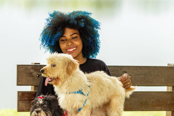 Eine junge Frau mit ihren beiden Hunden auf einer Parkbank. - Foto, Bild