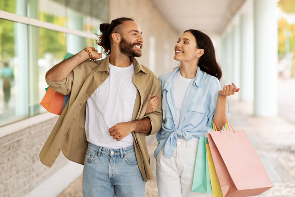 Positive young caucasian couple with many packages enjoy walk together, relationships, shopping and discount, outdoor. Huge sale in mall, lifestyle and free time, ad and offer - Photo, Image