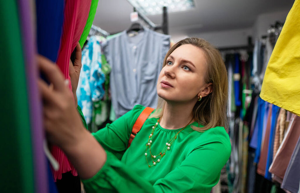 Woman choosing clothes in outlet store. - 写真・画像