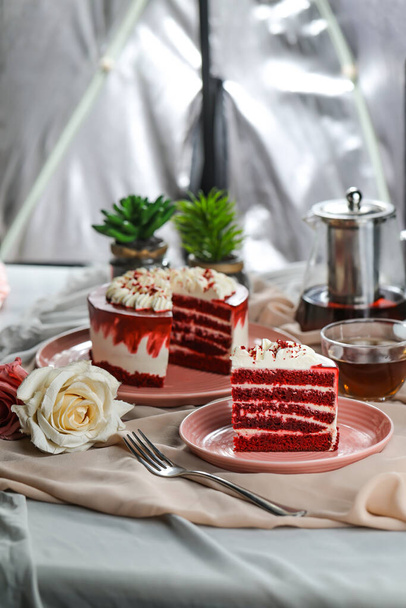 Premium Red Velvet cake and slice include cream, sugar with fork, cup of coffee and pot served on board isolated on napkin side view of cafe food - Photo, Image