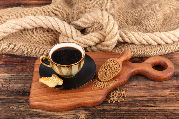 Onmiddellijke granulaat koffie. Koffiebonen op of instant granulaat koffie. Droge instant koffie in een zwarte keramische schotel naast koffiebonen geïsoleerd. - Foto, afbeelding