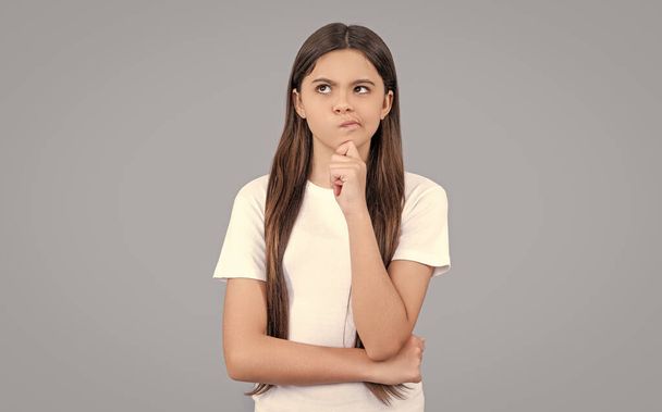 photo of pondering teen girl with long hair wearing tshirt. teen girl isolated on grey. teen girl in studio. teen girl on background. - Fotó, kép