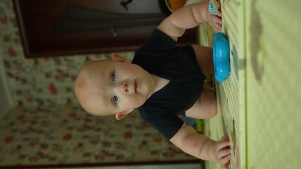 The little boy gets down on all fours, sways and tries to crawl. Leisure and development of an infant up to one year. Vertical video. High quality 4k footage - Footage, Video
