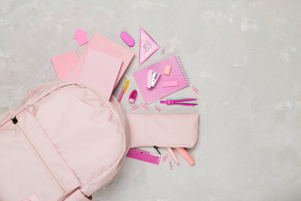 Mochila escolar rosa con papelería sobre fondo de hormigón, vista superior - Foto, Imagen