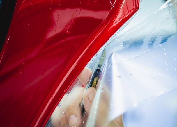 The process of installing protective film on the new red car - Fotografie, Obrázek