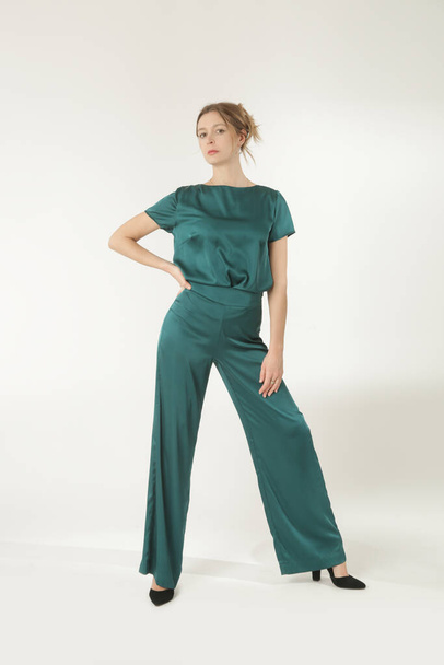 Serie studiofoto 's van jong vrouwelijk model in groene zijden outfit. - Foto, afbeelding