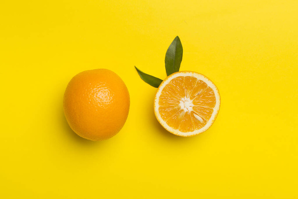 Flat lay with fresh oranges and leaves on color background. - Foto, imagen