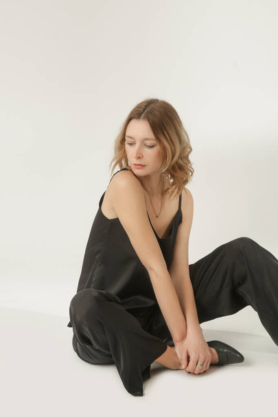 Serie of studio photos of young female model in black silk outfit, camisole blouse and wide legs trousers - Photo, Image