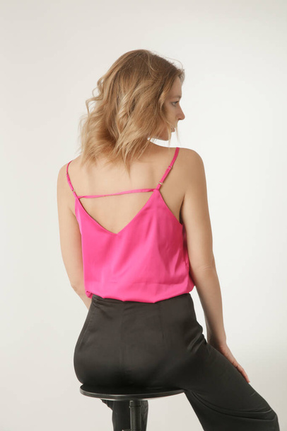 Seria zdjęć studyjnych młodej modelki w czarno-różowym jedwabnym stroju, bluzce z bluzką i szerokimi nogawkami - Zdjęcie, obraz