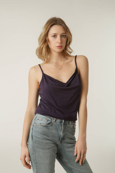 Female model wearing purple camisole cotton top and denim pants. Classic and simple summer fashion. Studio shot.  - Photo, Image