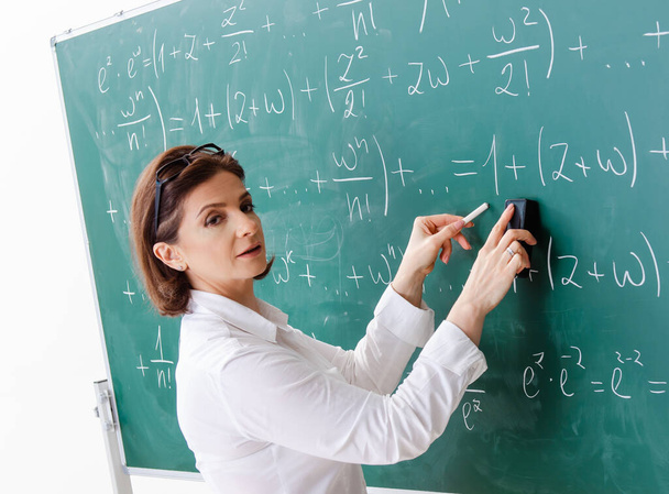 Η δασκάλα μαθηματικών μπροστά από τον πίνακα. - Φωτογραφία, εικόνα