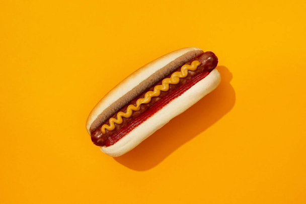 Klasyczny hot dog z wurstem, ketchupem i musztardą na pomarańczowym tle. Menu restauracji. Amerykańska kuchnia street food koncepcja - Zdjęcie, obraz