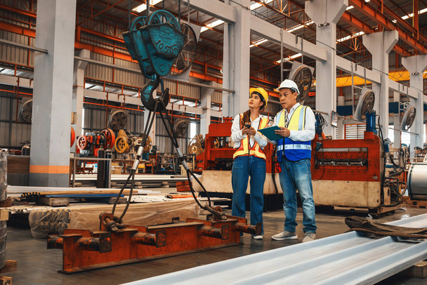 Brygadzista fabryki i inżynier przeprowadzają inspekcję maszyn przemysłowych ze stali i wysokiej jakości materiałów metalowych. Zakład produkcyjny z bezpieczeństwem maszyn i kontrolą jakości. Przykładowo: - Zdjęcie, obraz