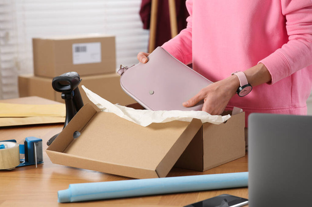 Seller packing bag into cardboard box at table in office, closeup. Online store - Photo, image