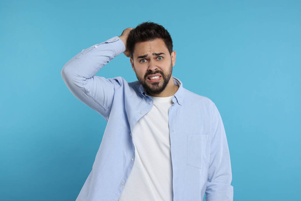Portrait of embarrassed man on light blue background - Photo, image