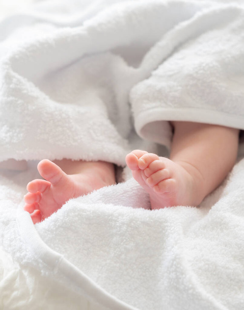 Los pies de un recién nacido puro y suave vistazo de una toalla blanca que simboliza la vida suave comienzo después de un baño calmante - Foto, imagen