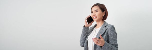 Молода елегантна жінка говорить на мобільному телефоні на фоні білого банера - Фото, зображення