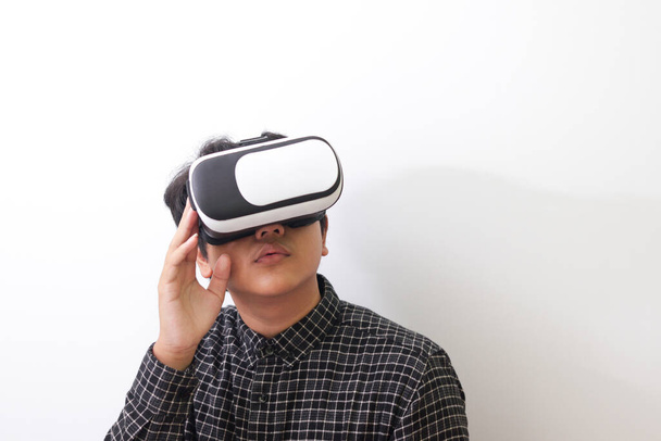 Retrato de hombre asiático en camisa a cuadros negro usando gafas de Realidad Virtual (VR) y mirando hacia arriba. Imagen aislada sobre fondo blanco - Foto, imagen