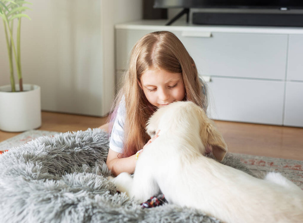 Meisje speelt thuis met een golden retriever puppy. Vrienden thuis. - Foto, afbeelding