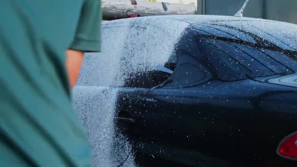Mycie luksusowego czarnego samochodu na bezdotykowej myjni. Sprzątam szczegóły samochodu. Mycie samochodu sedan z pianką samoobsługową i wysokim ciśnieniem wody. Czystość i porządek w środowisku miejskim - Materiał filmowy, wideo